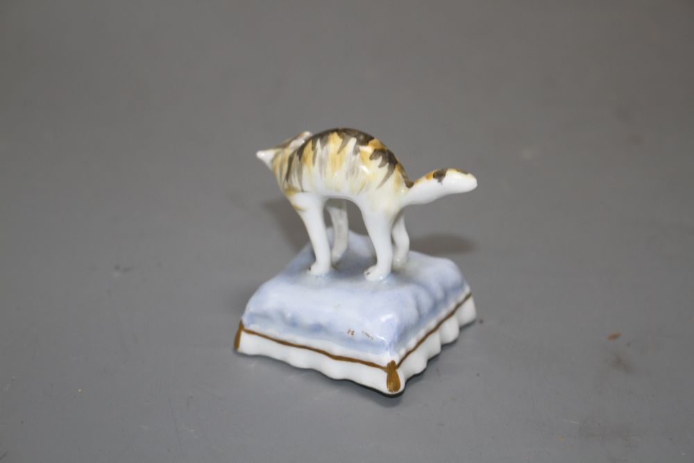 A rare Staffordshire toy porcelain figure of a cat with arched back, on a cushion, c.1835-50, H. 4.6cm